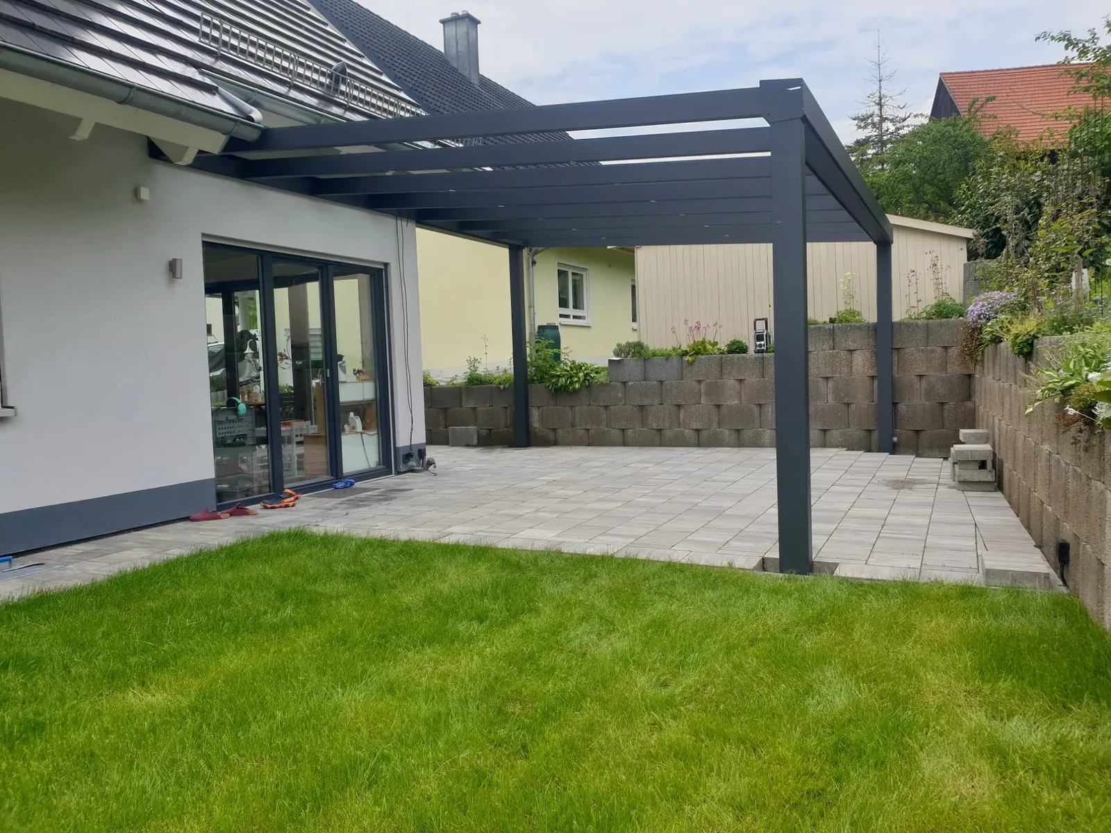 Anthrazitfarbene Aluminium Terrassenüberdachung auf Pflasterterrasse