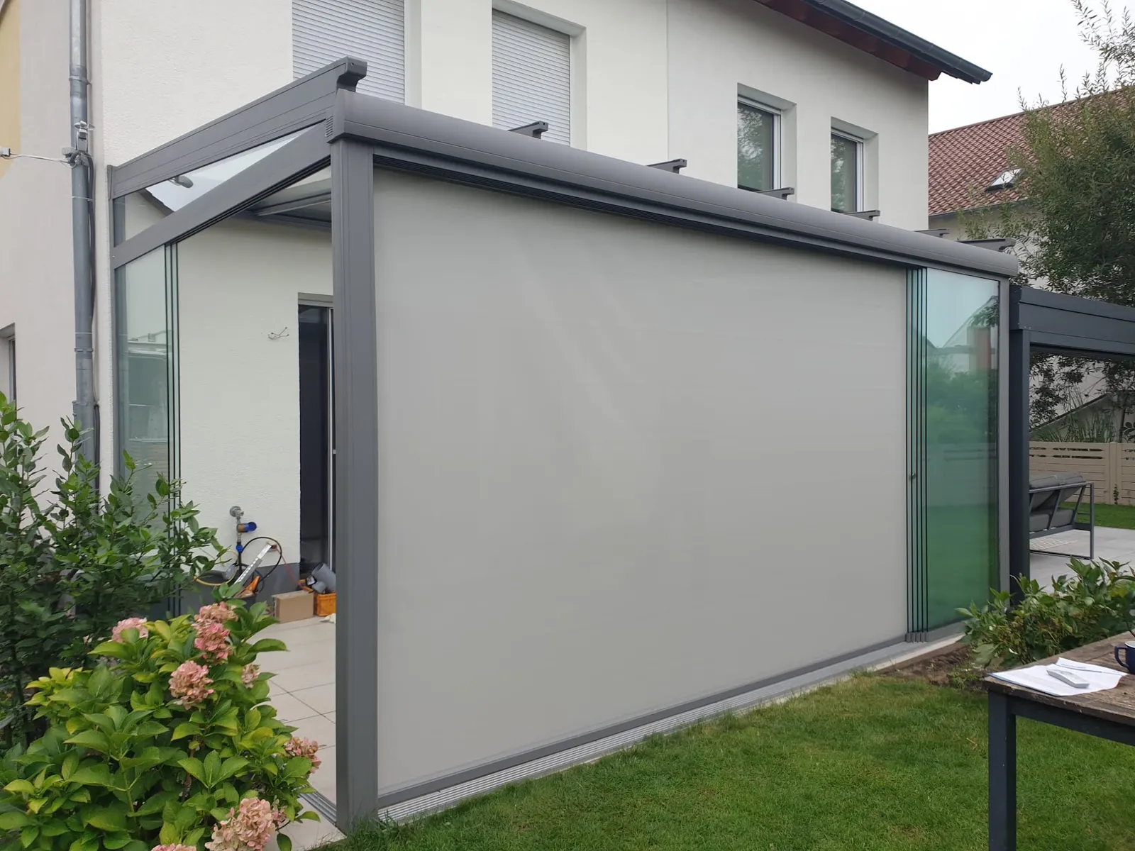 Eingefasstes Glas-Terrassendach mit vertikaler Senkrechtmarkise