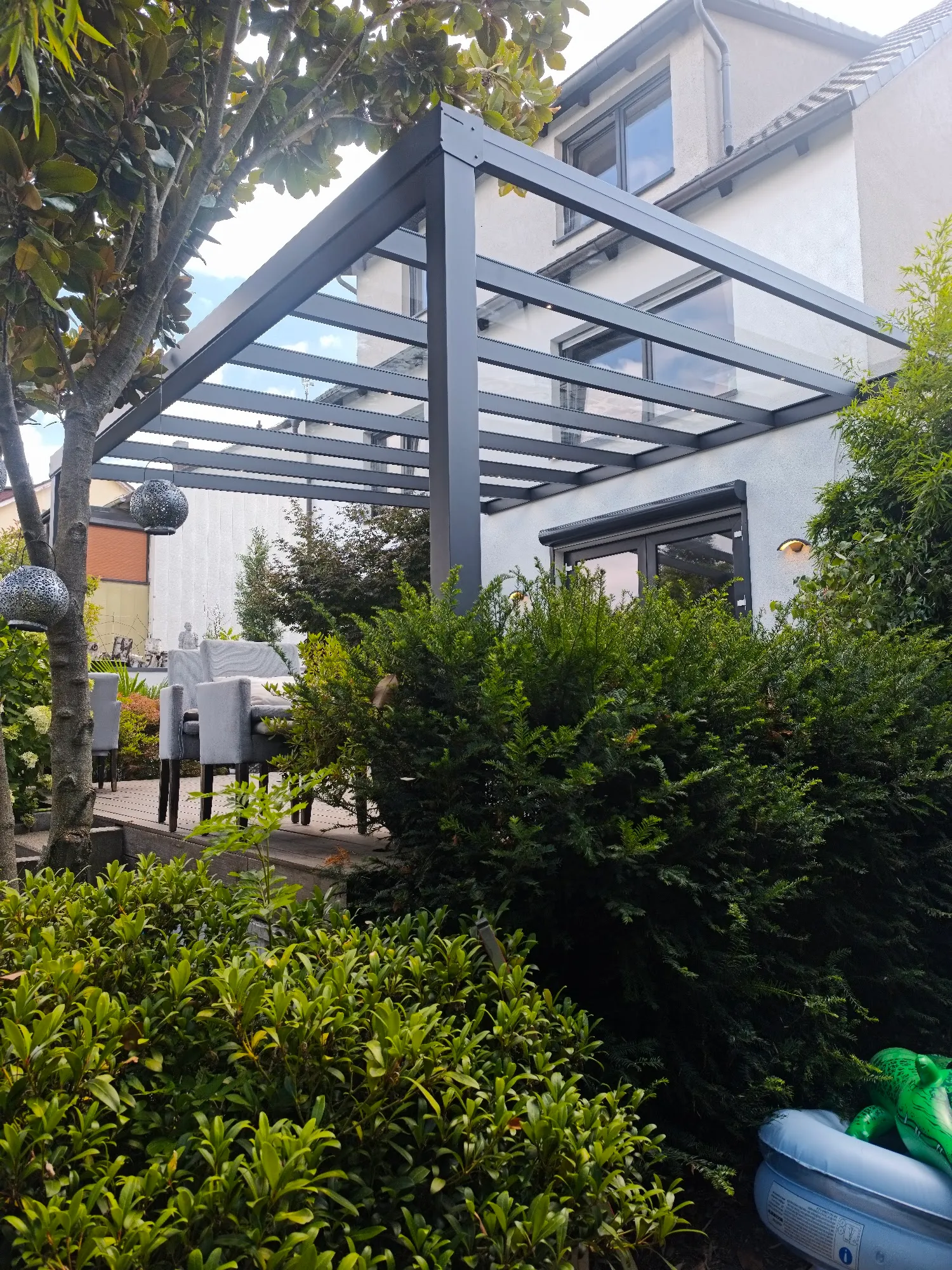 Anthrazit Pergola mit Glasdach und geschützter Lounge-Gartenbereich